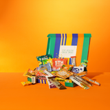 Zakelijke box met gezonde tussendoortjes en snackproducten op een oranje achtergrond.